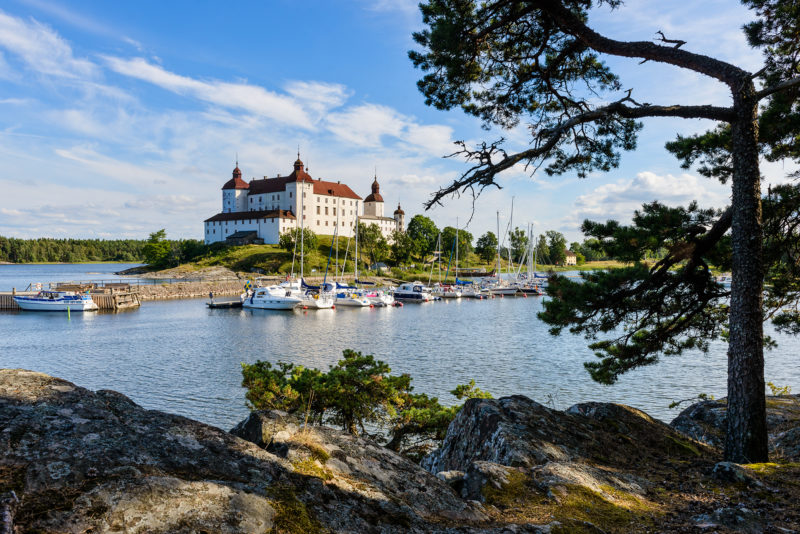 Bild mot Läckö slott med en båthamn nedanför.