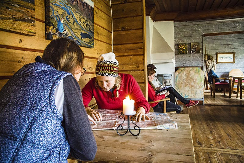 Två kvinnor sitter böjda över fjällkartan vid ett bord på Saltoluoktas fjällstation.