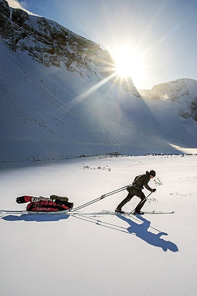 En skidåkare drar en tung pulka i en dalgång i Kirunafjällen.