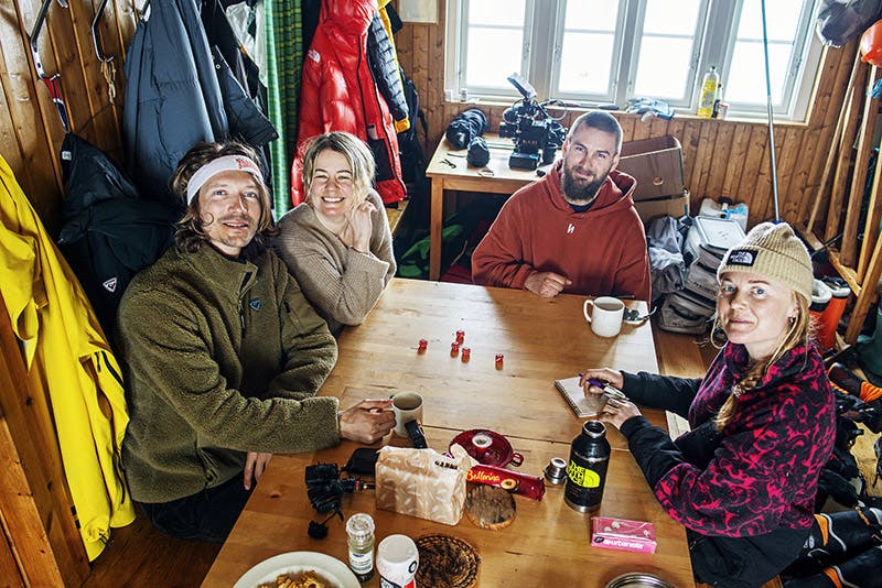 Fyra personer sitter runt ett bord och fikar och spelar tärning.