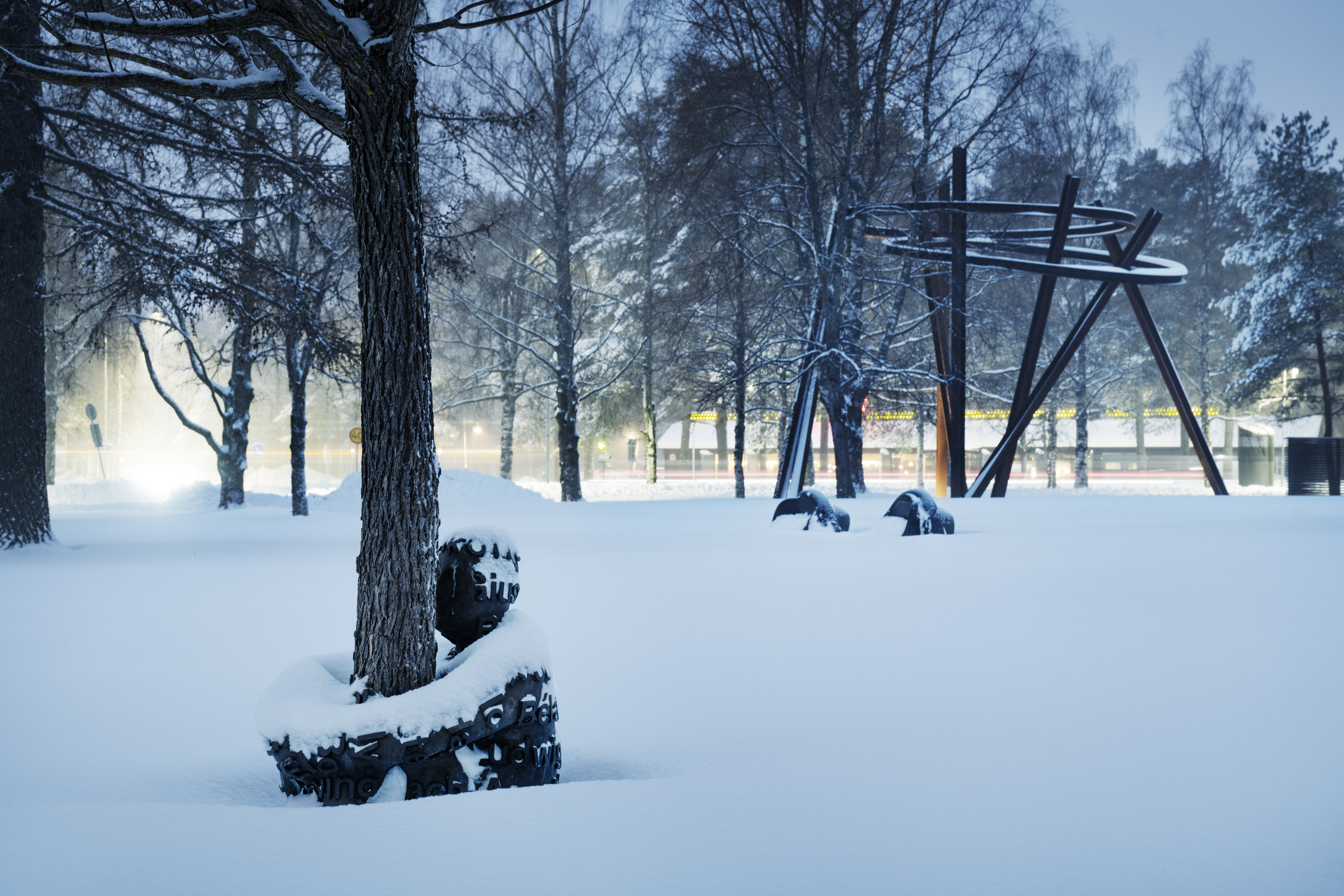 En bronsstaty föreställande en människa som kramar ett träd, täckt i snö i Umedalens skulpturpark.