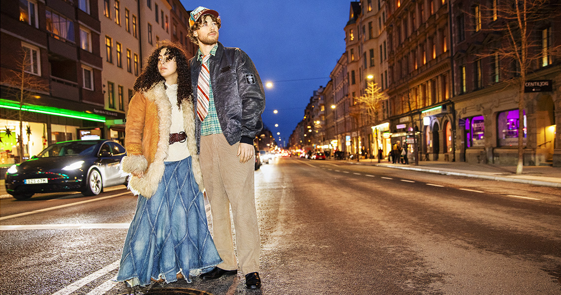 En kvinna och en man poserar mitt på Hornsgatan iklädda kläder köpta begagnat