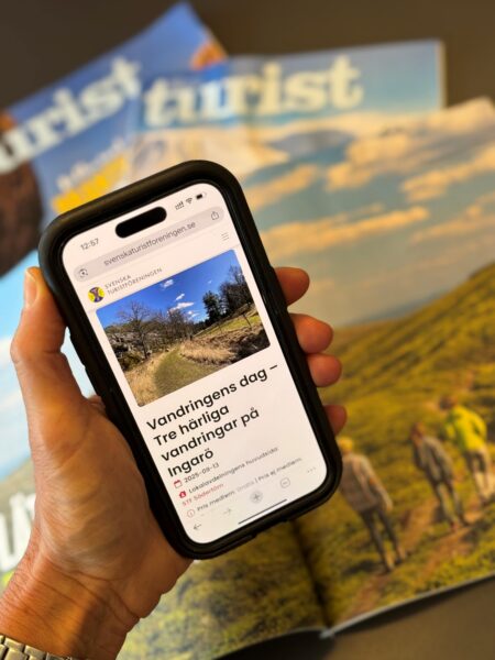 hand som håller mobilskärm med information om Vandringens dag.