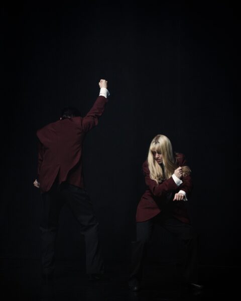 Siluetter av kostymklädda personer i ett mörkt rum.