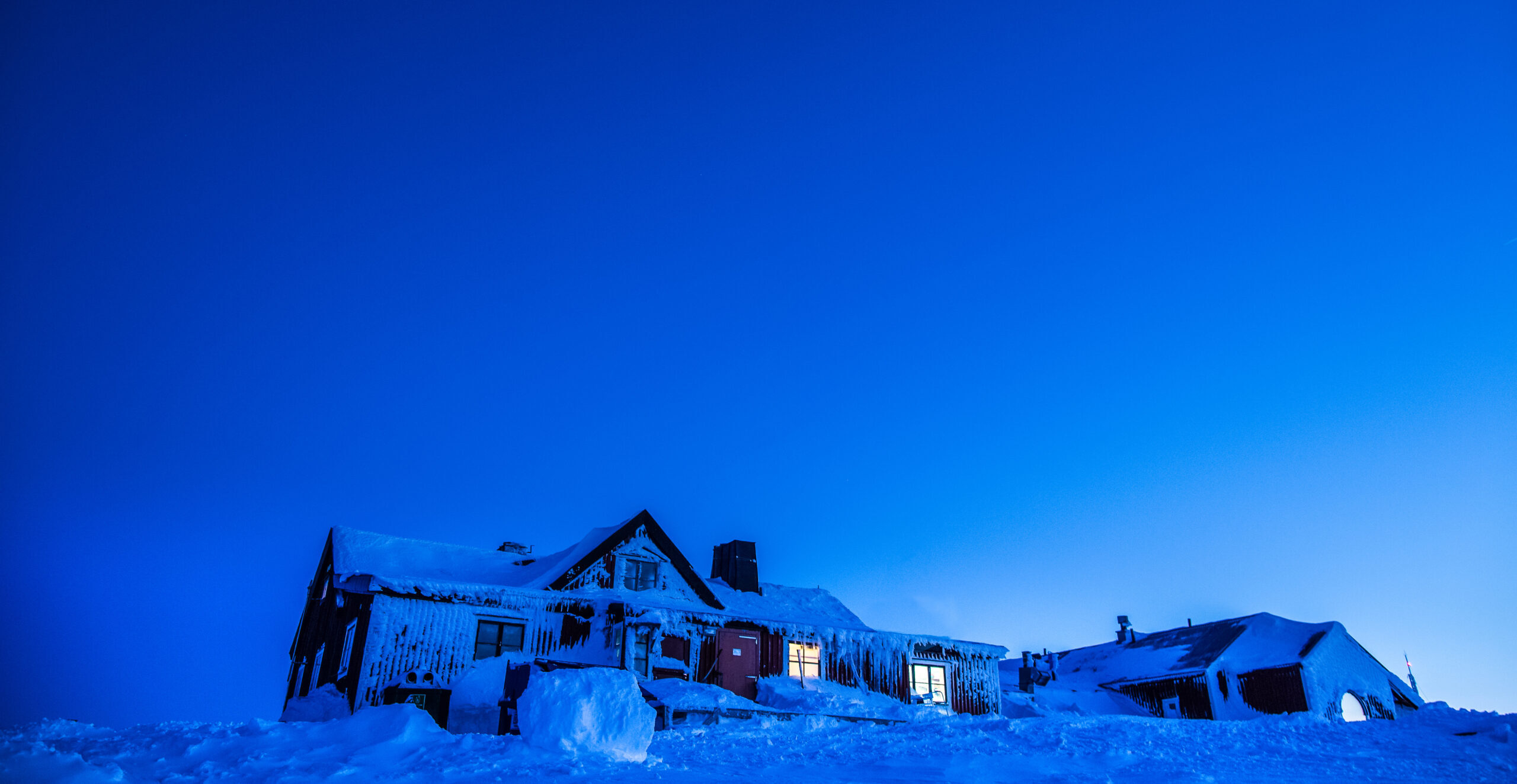 Blåhammarens fjällstation i vinterskrud och skymningsljus.