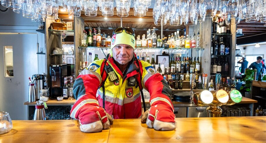 En fjällräddare i arbetskläder bakom en bardisk.