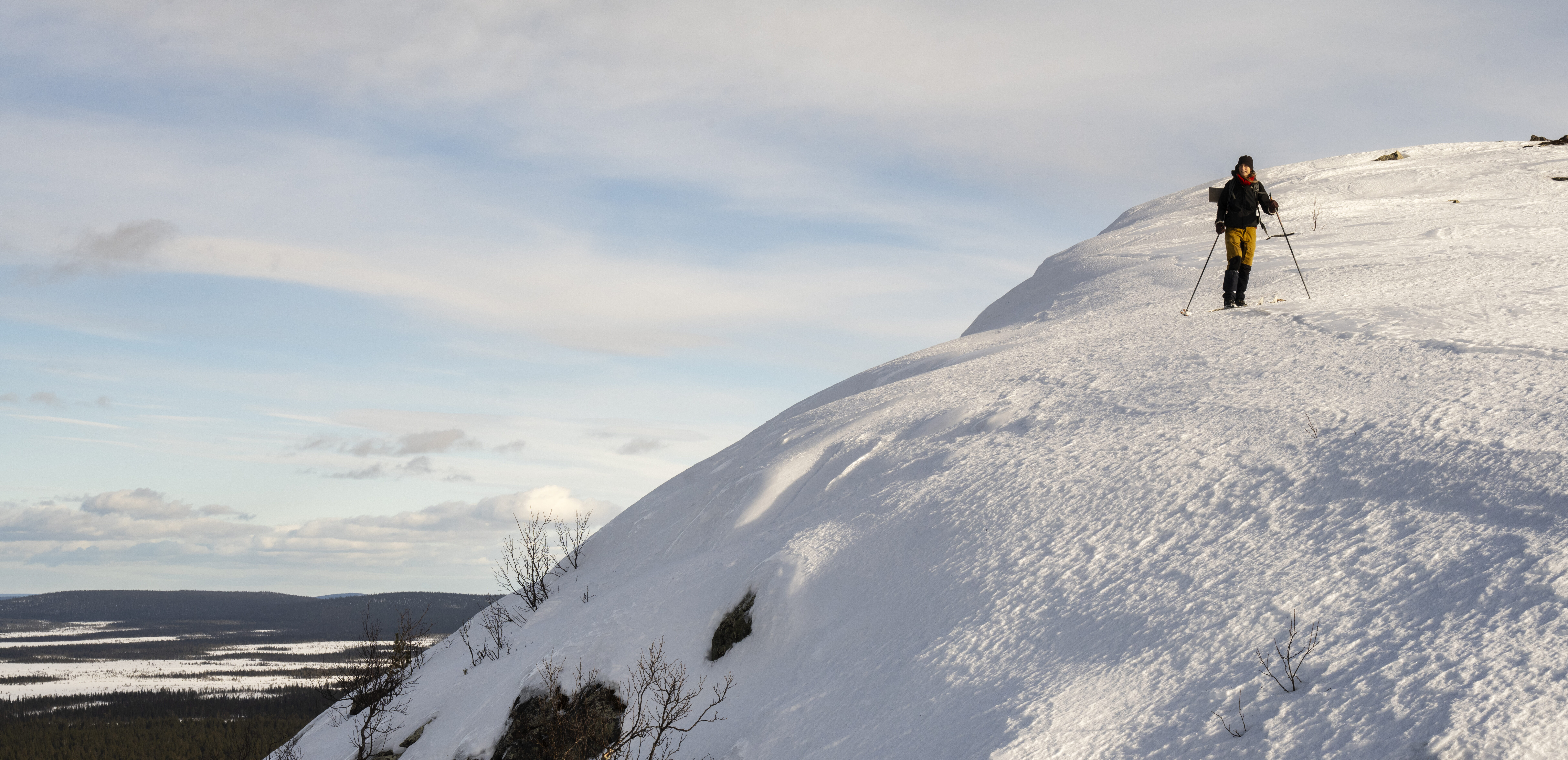 Person uppe på ett snöklätt berg i Muddos nationalpark.