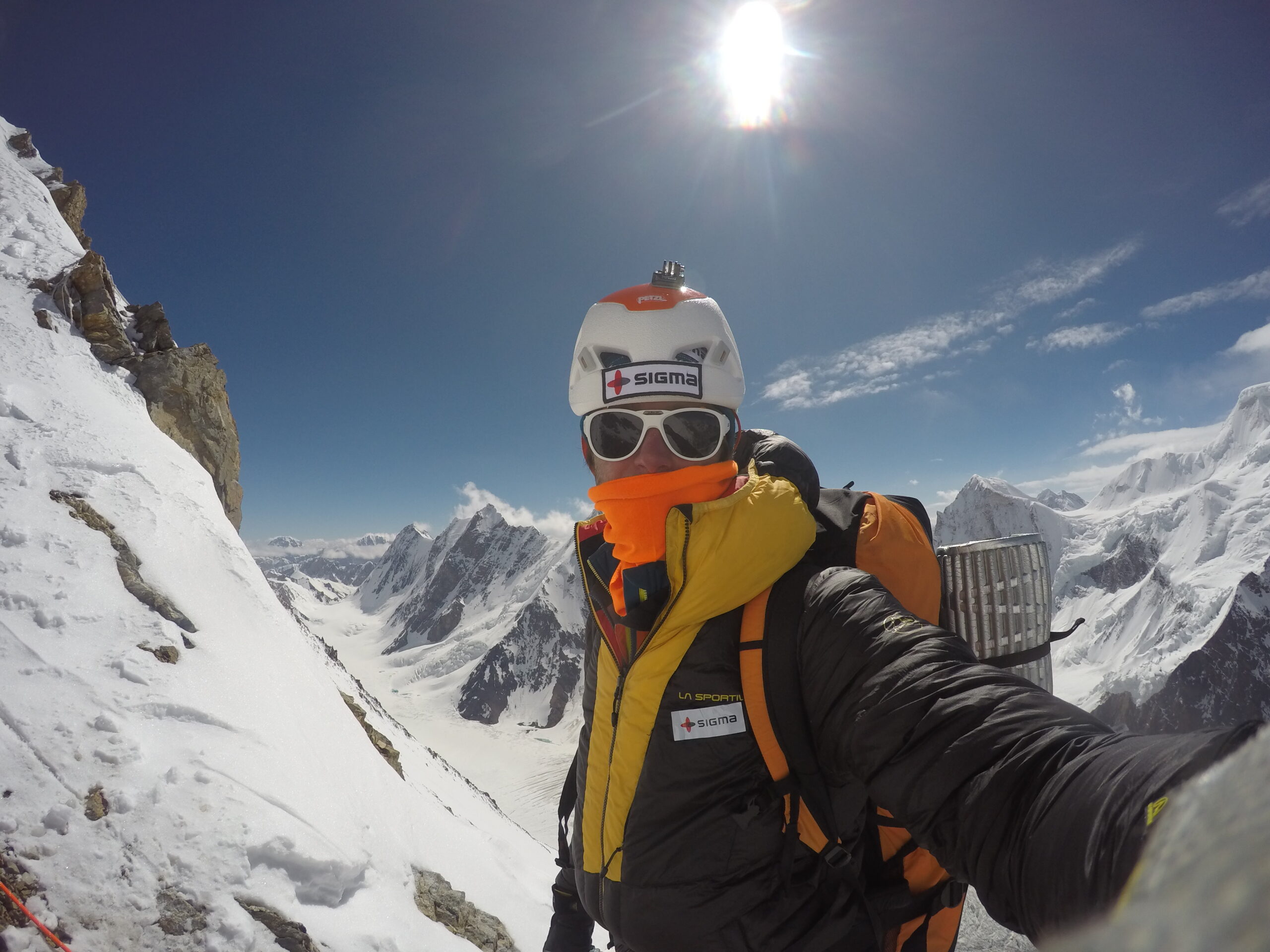Person på äventyr tar en selfie av sig själv från ett snöklätt berg med sol och klarblå himmel i bakgrunden.