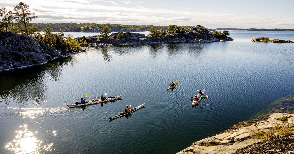 Fyra kajaker på ett spegelblankt hav i Grytstriangeln.