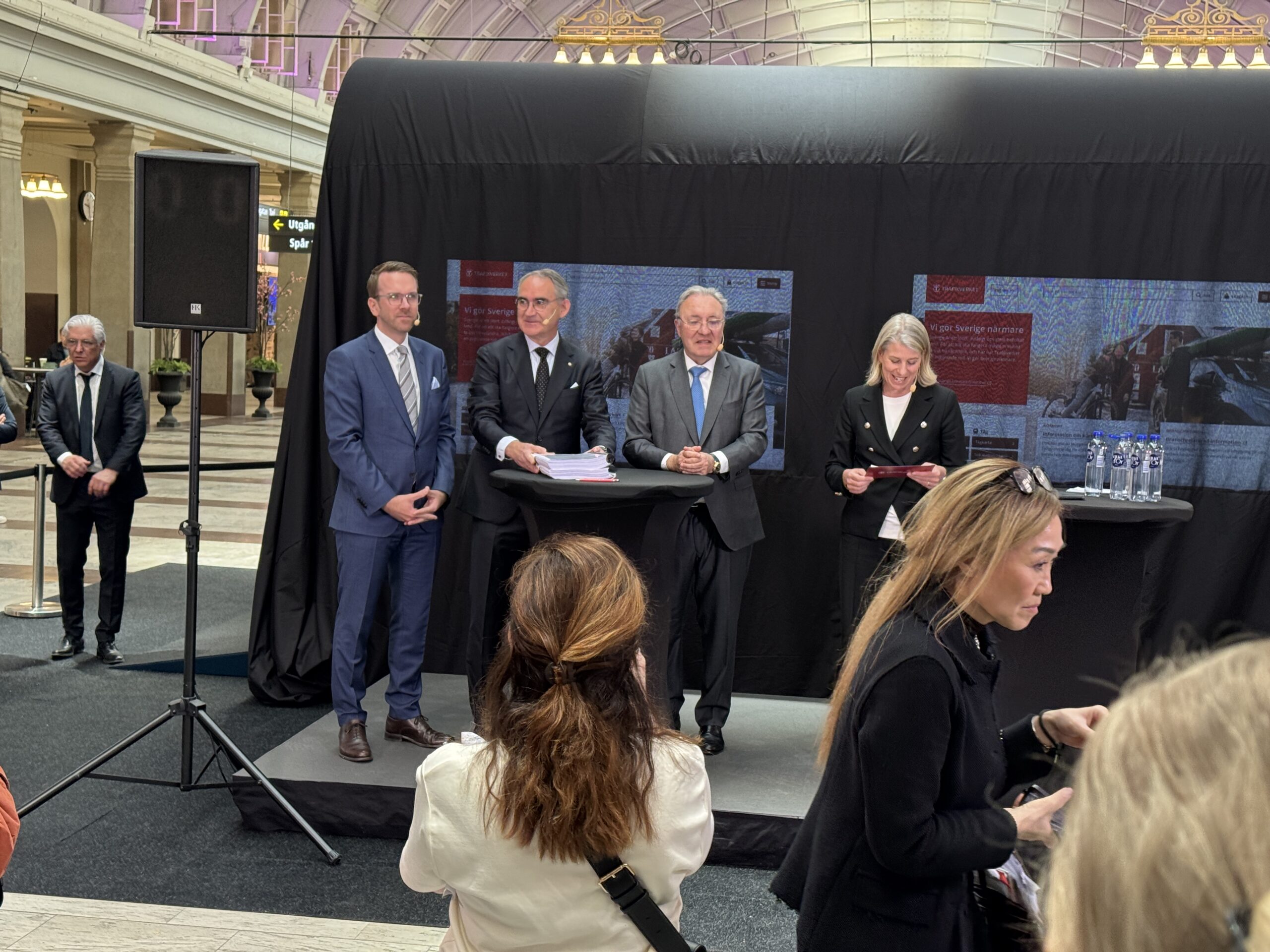 Tre män och en kvinna i kostym framför prototypen till Trafikverkets nya nattåg.