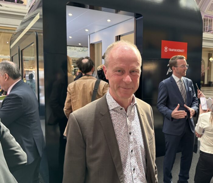 Man i grå kavaj framför ett av Trafikverkets nya nattåg.