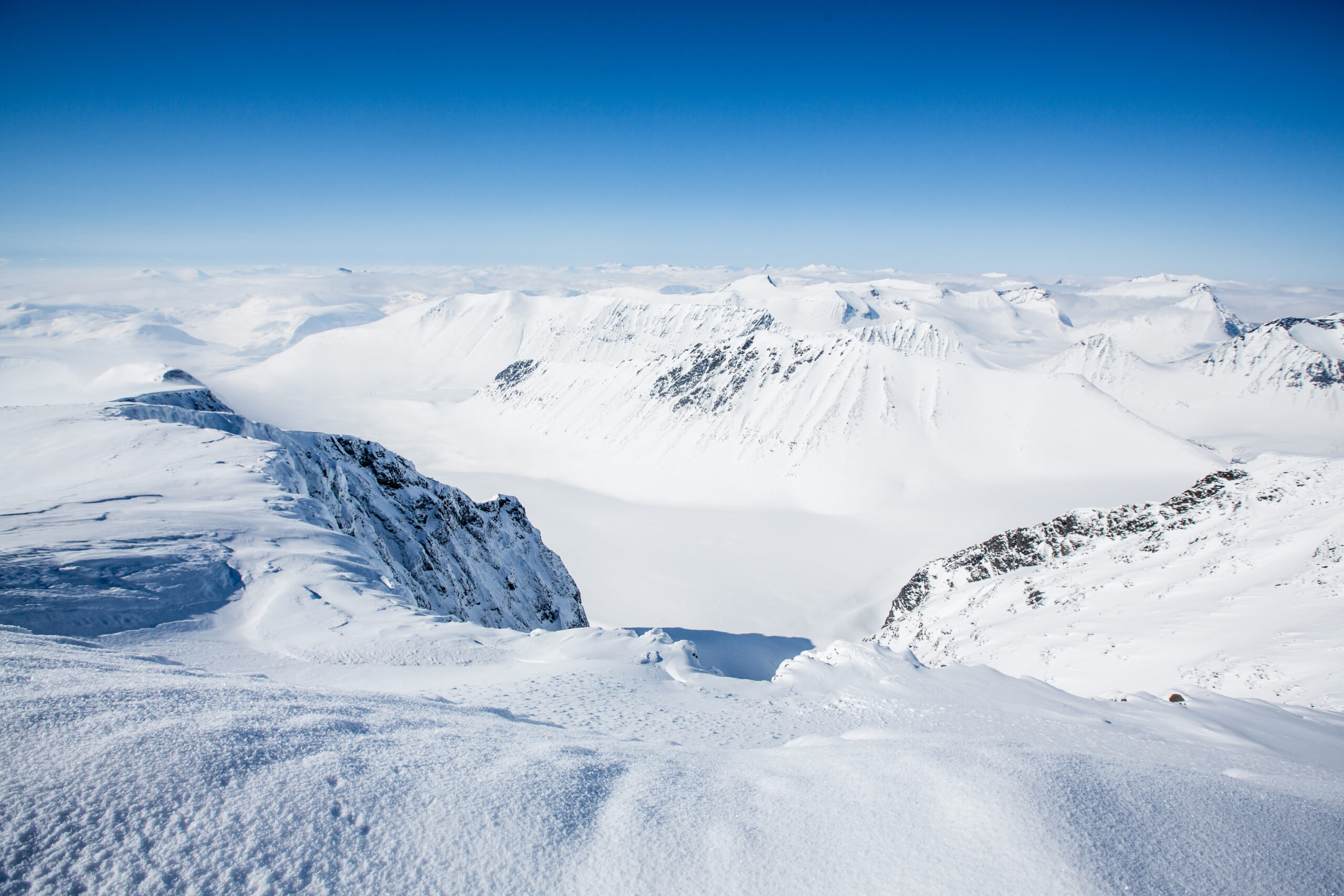 Snötäckta fjälltoppar mot en blå himmel i närheten av Halspasset.
