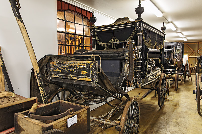 En hästdragen likvagn med flagnad färg inne i museet i Öddeshög.