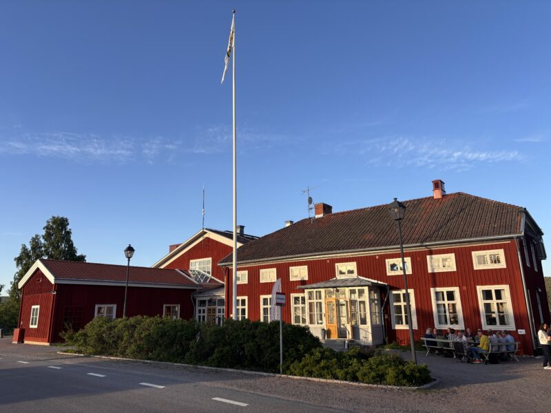 En röd mangårdsbyggnad med en flaggstång vid uppfarten.