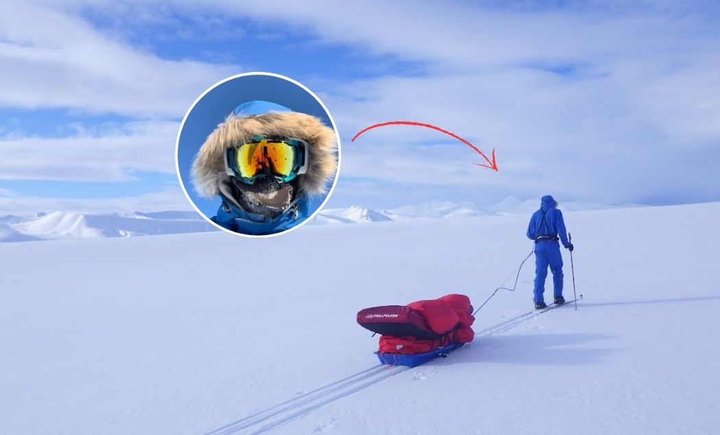 En bild på en blåklädd person som drar en röd pulka i ett snötäckt landskap.