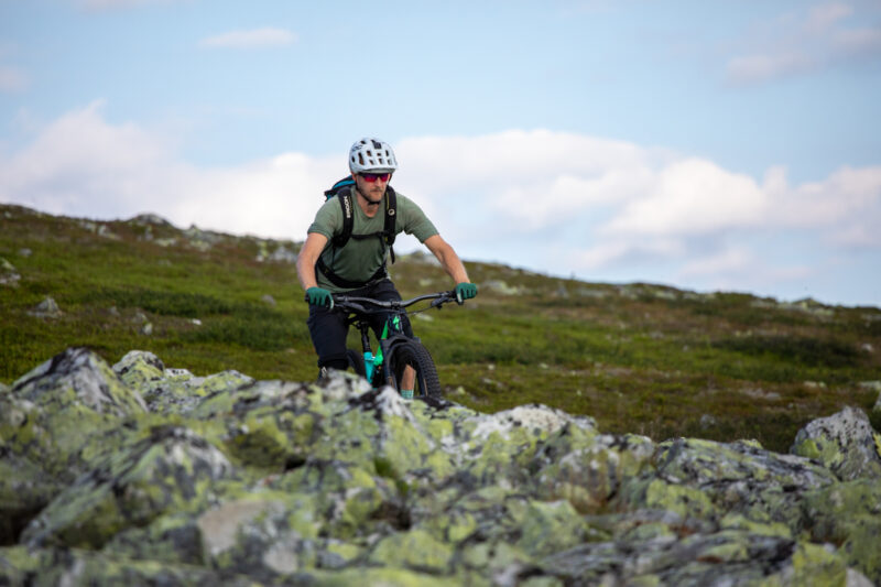 En cyklist på fjället med en mossbelupen sten i förgrunden.